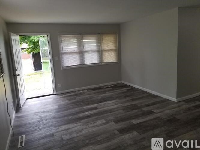 A room with a wooden floor and a window with blinds.