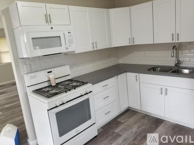 A white kitchen with a stove, microwave, and cabinets.