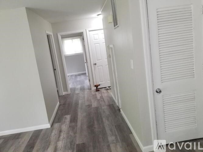 A hallway with a wooden floor and white walls.
