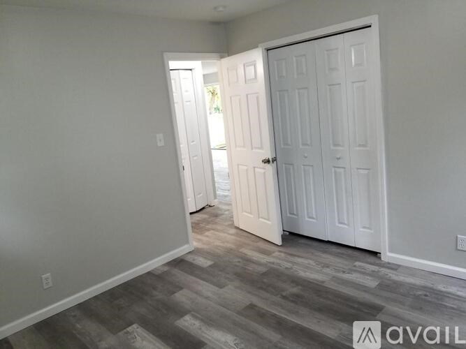 A room with a white door and a wooden floor.
