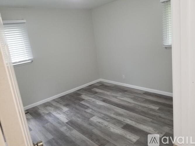 A room with a wooden floor and a window with blinds.
