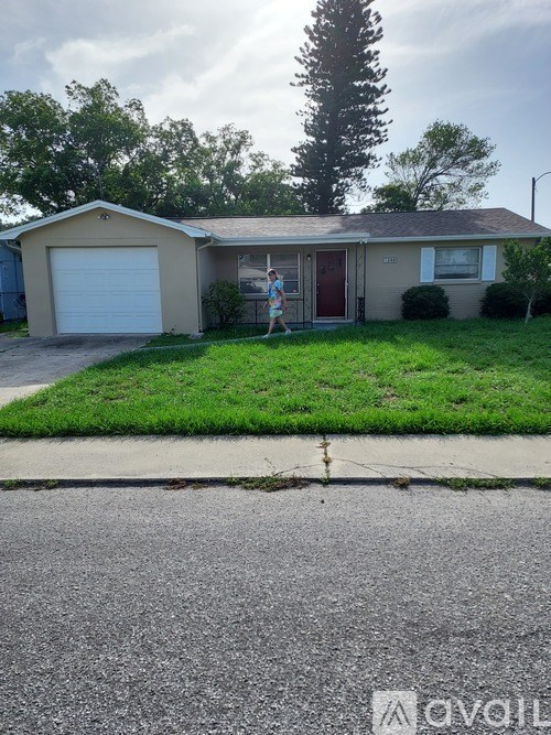 A house with a brown roof and a red door is surrounded by green grass.
