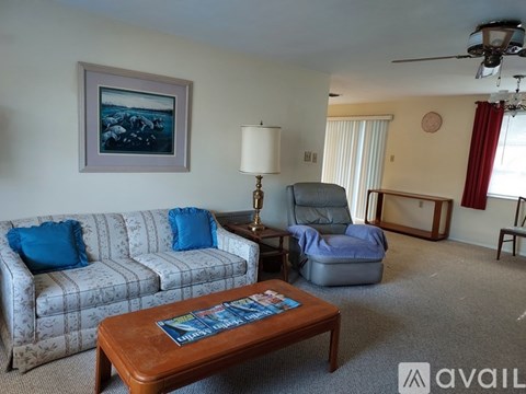 A living room with a sofa, a chair, a coffee table, and a painting on the wall.