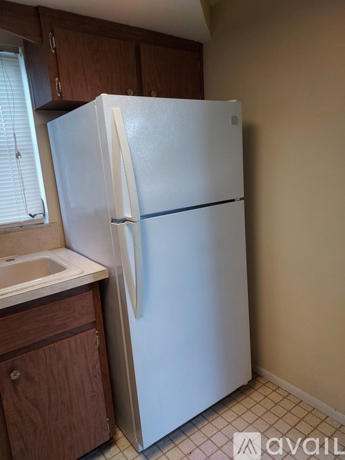 A white refrigerator in a kitchen with brown cabinets.