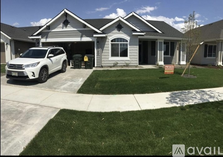 A white car is parked in front of a house with a sign that says "For Sale".