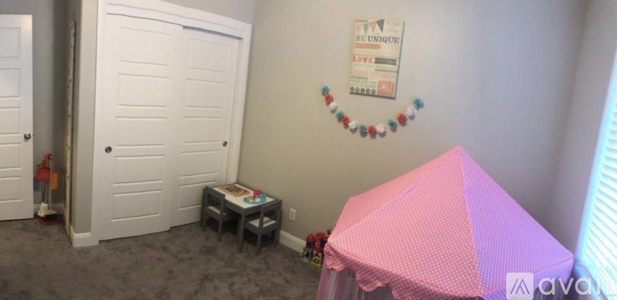 A pink and purple tent is set up in a room with a white door and a wall hanging.