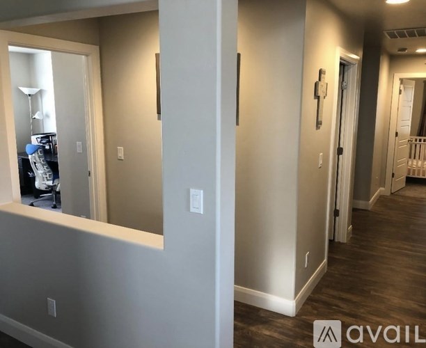 A hallway with a mirror on the wall and a door on the right.