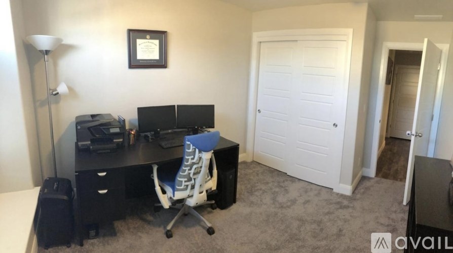 A room with a desk, chair, and a framed picture on the wall.