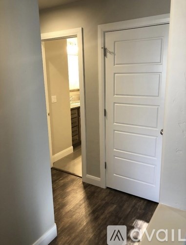 A white door is in a hallway with wood flooring.
