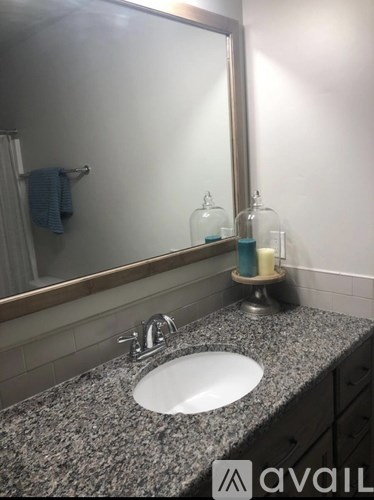 A bathroom sink with a granite countertop and a mirror above it.