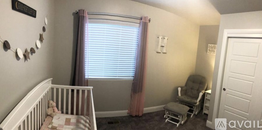 A baby room with a crib, a chair and a window.