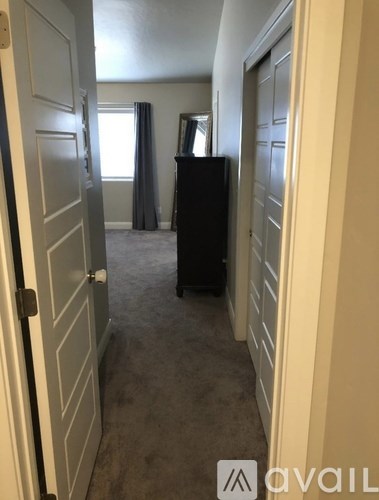 A room with a black refrigerator and a grey carpet.