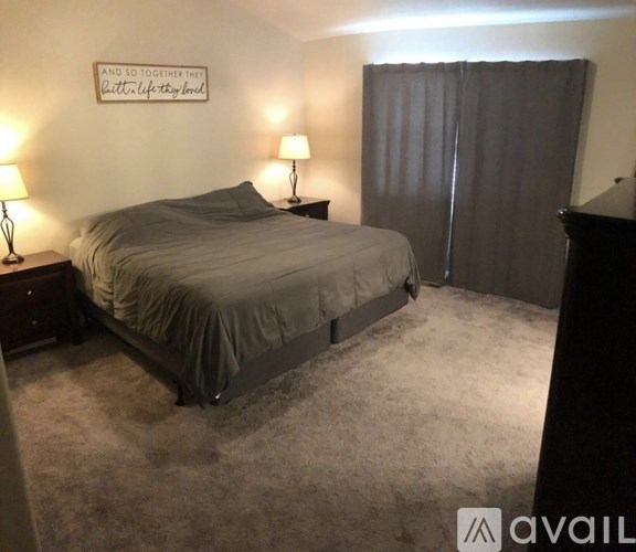 A bedroom with a bed, two lamps, and a sign on the wall.