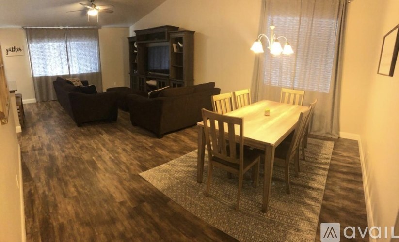 A living room with a brown couch, a white dining table, and a television.