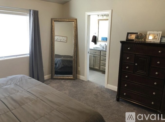A bedroom with a large bed, a dresser, and a mirror.