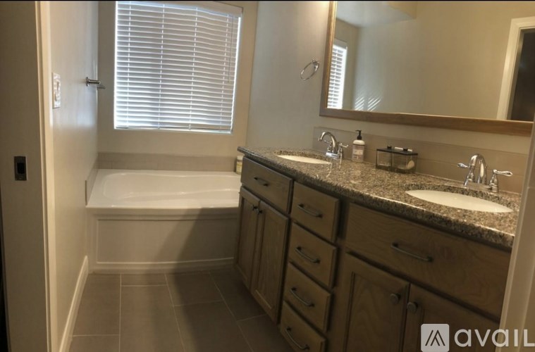 A bathroom with a tub, sink, and mirror.