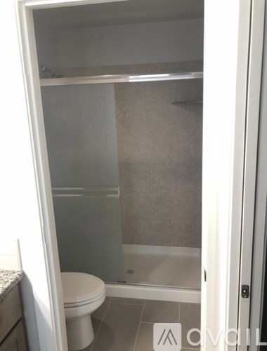 A white toilet is in a small bathroom with a glass shower door.