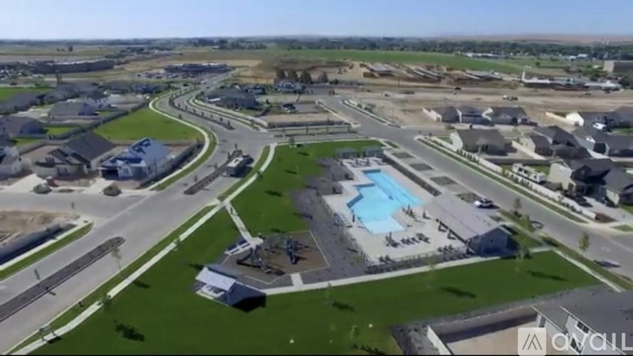 A bird's eye view of a residential area with houses, roads, and a swimming pool.