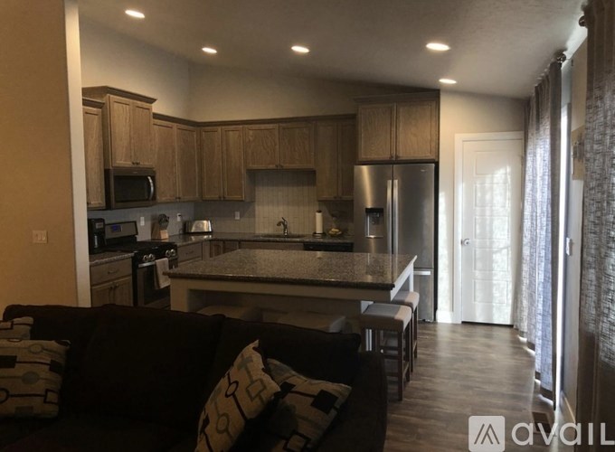 A modern kitchen with a black couch and wooden cabinets.