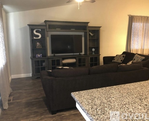 A living room with a brown couch and a television on a wooden stand.