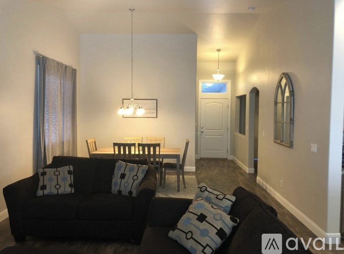 A living room with a black couch and a dining table.