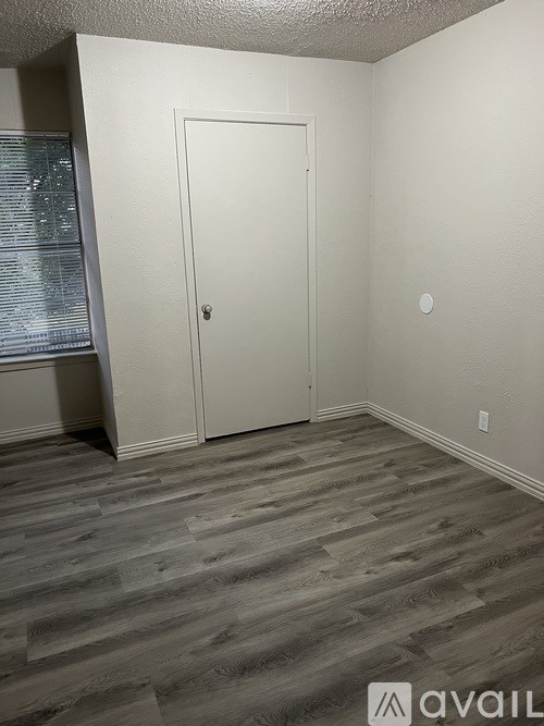 A room with a white door and wooden flooring.