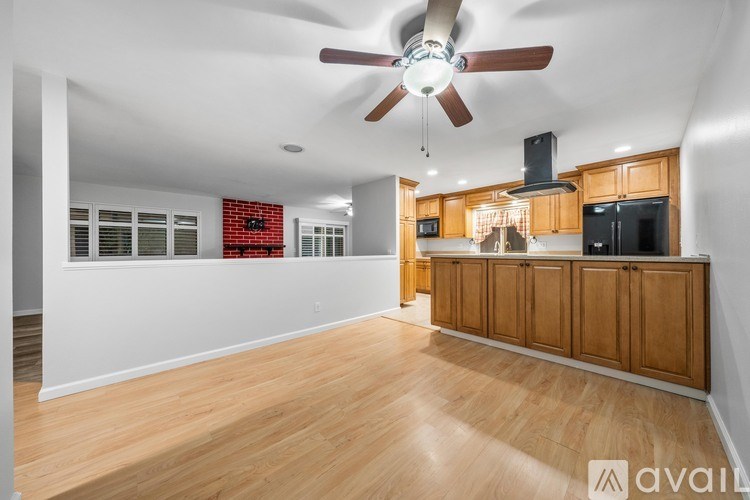 A spacious room with wooden flooring and a ceiling fan.