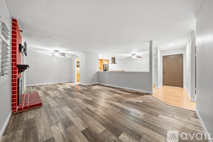 A spacious room with wooden flooring and white walls.