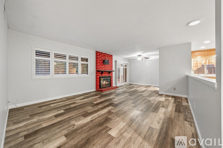 A room with wooden flooring and a red brick wall with a fireplace.