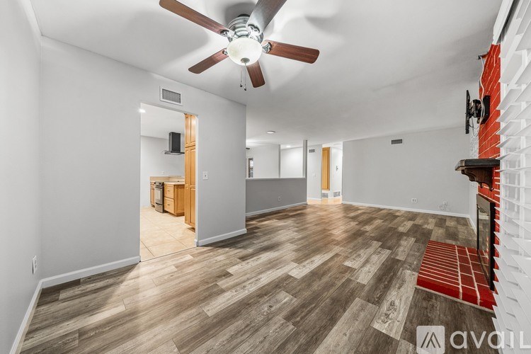 A room with a ceiling fan and wooden flooring.