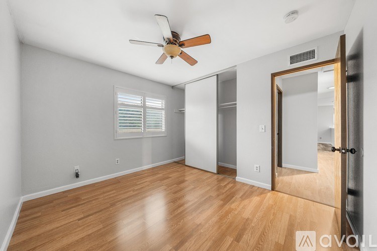 A room with a ceiling fan and wooden flooring.