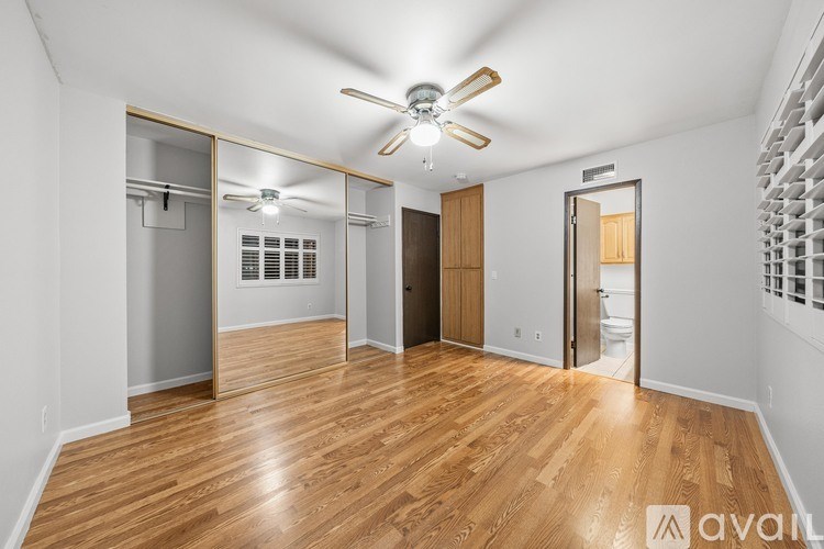 A spacious room with wooden flooring and a ceiling fan.