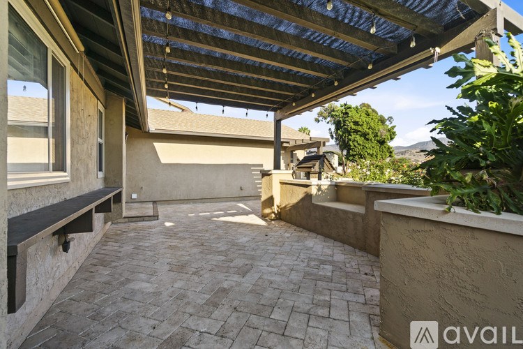 A patio with a roof and a bench.