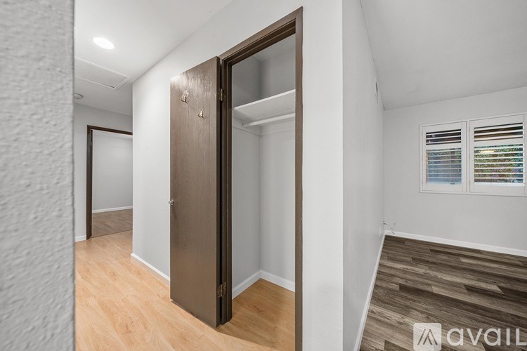 A room with a wooden floor and a white wall with a brown door.