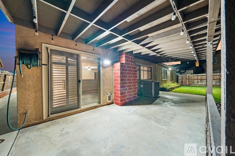A covered outdoor patio area with a brick wall and a hose.