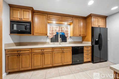A kitchen with wooden cabinets and black appliances.