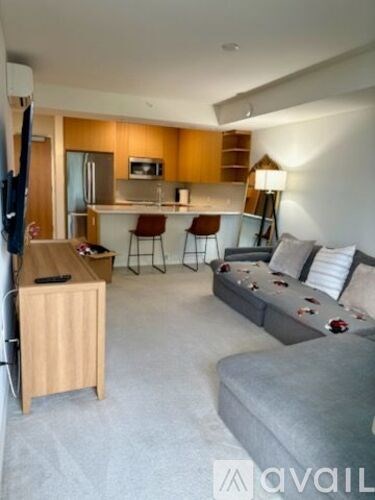 A living room with a grey couch and a wooden cabinet.