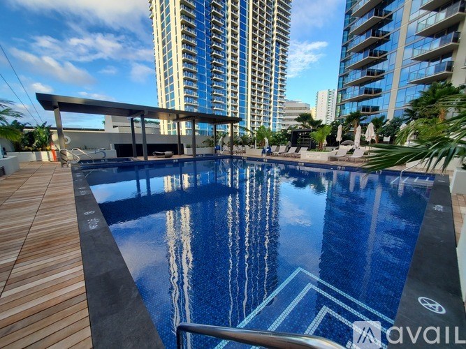 A pool with a wooden deck and a building in the background.