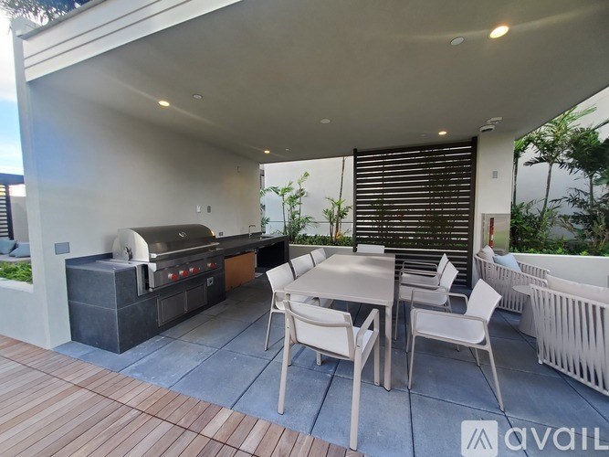A patio with a table, chairs, and a grill.