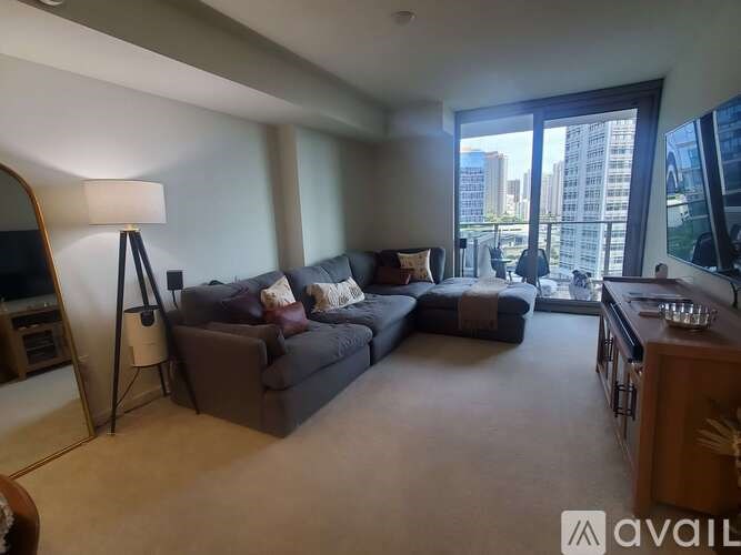 A living room with a grey couch and a lamp on a tripod.