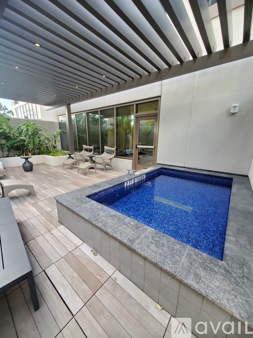 A modern outdoor pool area with a stone border and a glass door.