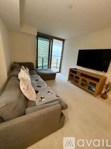 A living room with a grey couch and a flat screen TV mounted on the wall.