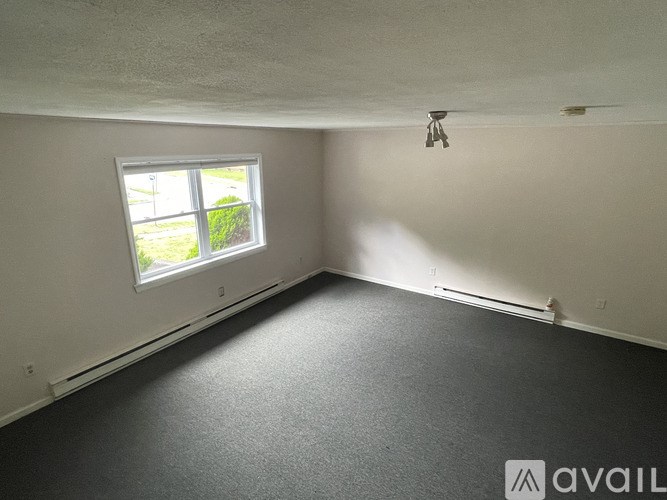 A room with a window and a carpeted floor.