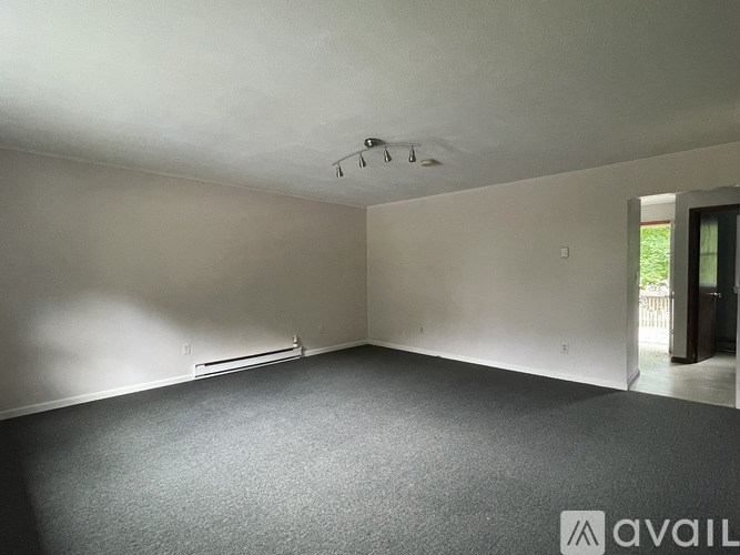 A room with grey carpet and white walls is available for rent.