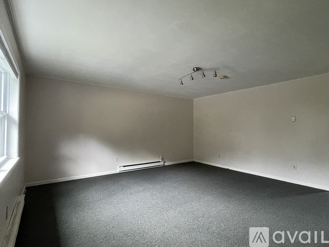 A room with a carpeted floor and a window on the left side.