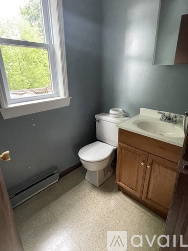 A bathroom with a toilet, sink, and window.