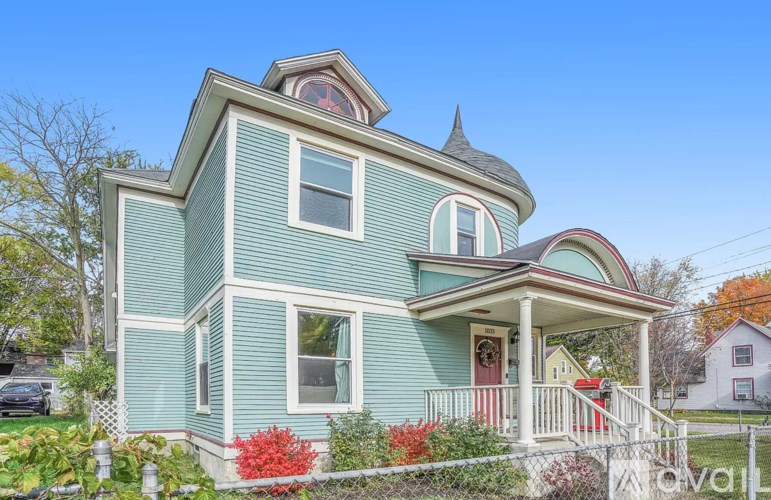 A blue house with a red door and a white fence.
