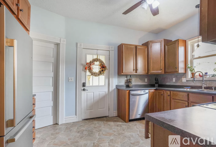 A kitchen with wooden cabinets and a stainless steel dishwasher.
