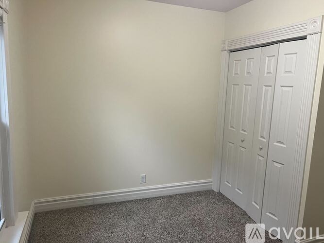 A room with a white door and carpeted floor.