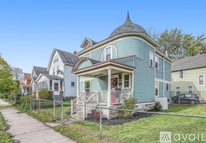 A blue house with a porch and a fence in front.